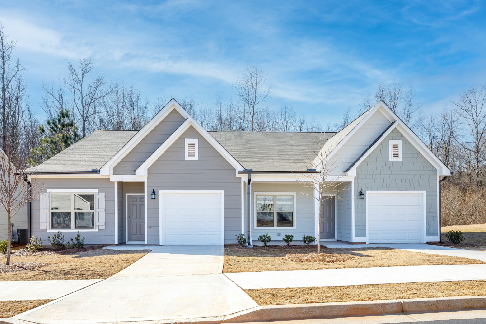 Exterior shot of grey in color townhomes with garages
